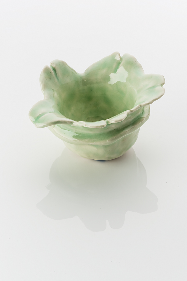 Hand made ceramic bowl made from a white clay body, washed over with a pale green shiny glaze. The rim of the bowl opens up with leave like petals. A raised protuding line on the outer surface marks the mid point of the bowls form.